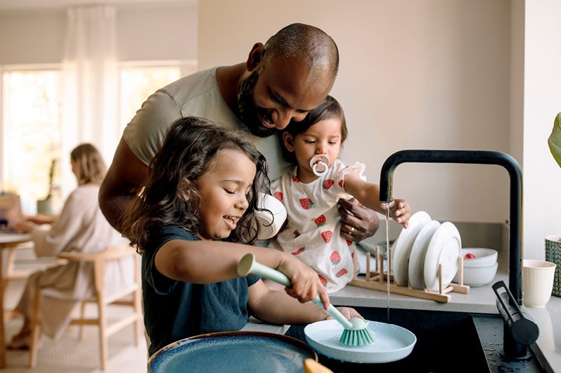 A father washing dishes with his children