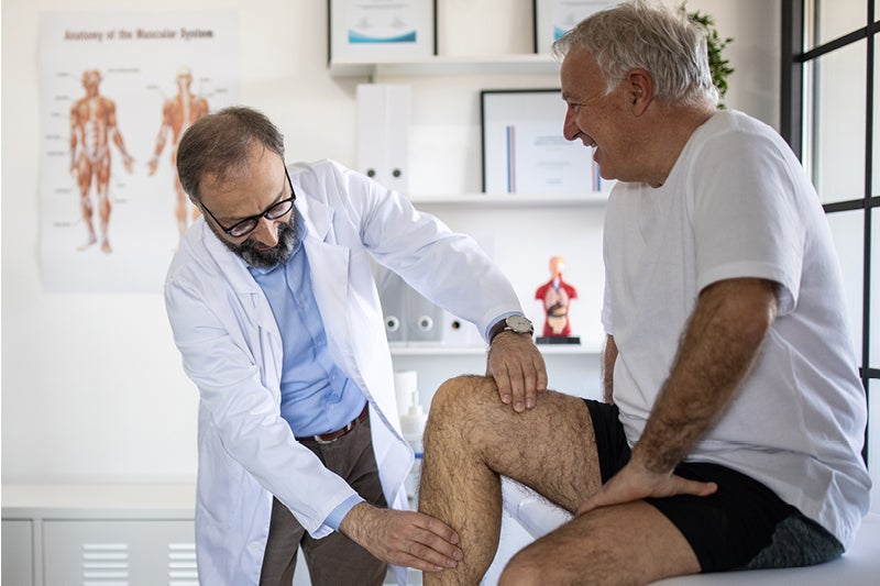 Doctor examining man's knee