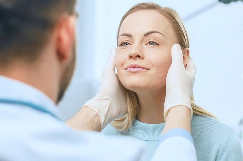 Doctor examining a female patient's face