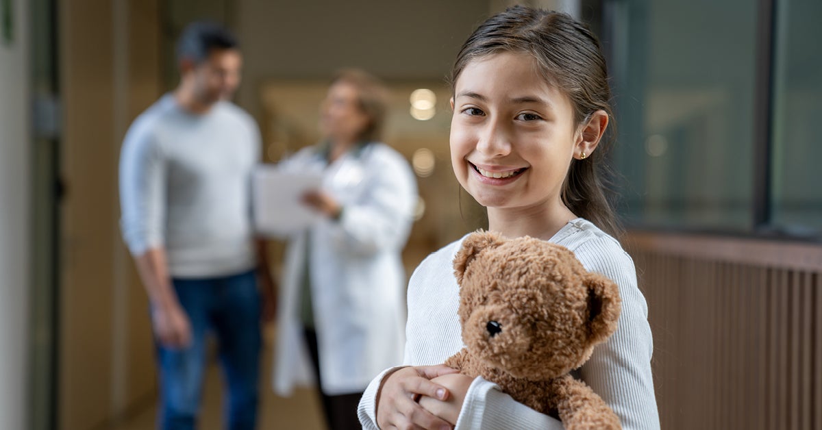 child standing in hospital hallway smiling