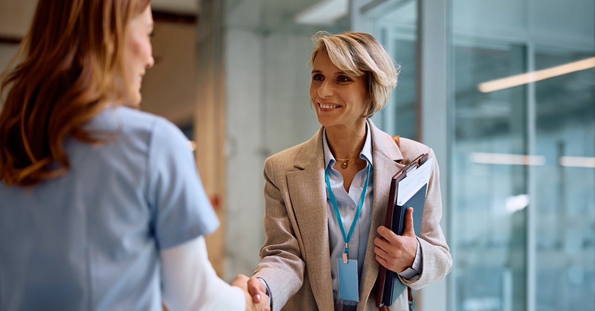 woman shaking hands with another in professional setting