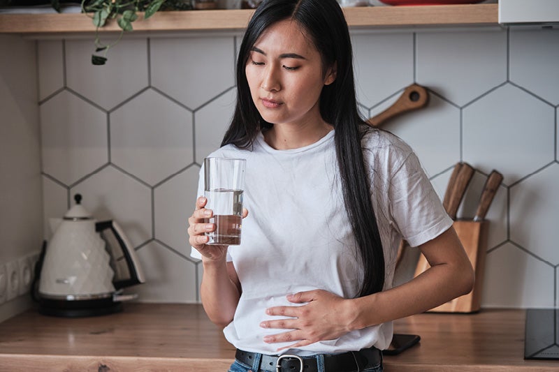 Woman holding a glass of water in pain