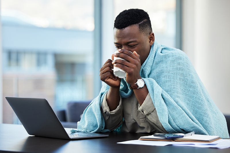 Man sitting at his computer sipping on a warm drink
