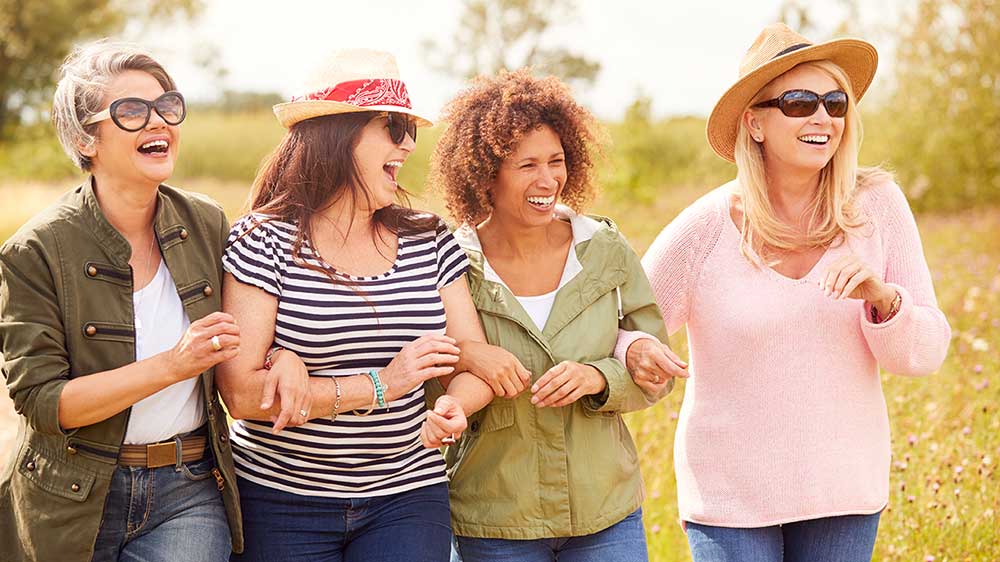 four women laughing while walking outside