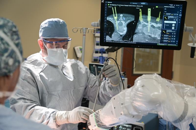 A surgeon is shown using robotic technology to perform spine surgery.